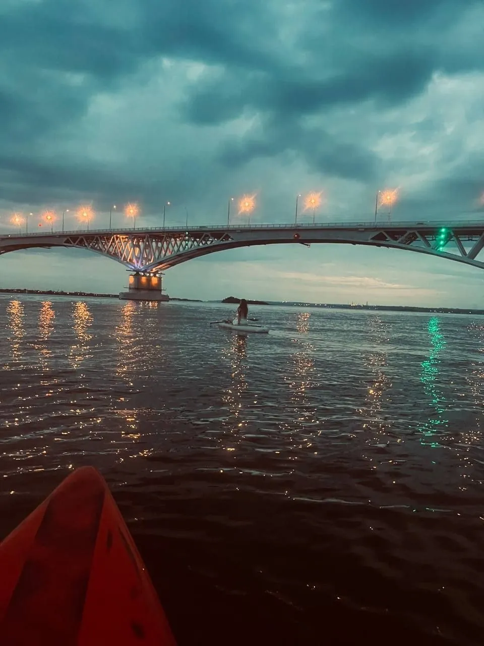 Сапбордист под мостом на закате
